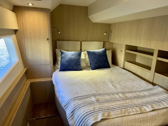 Roosterfish Yacht Photos Pics Luxurious bedroom interior of 2022 Aquila 44 yacht with modern wood finish and cozy bedding.