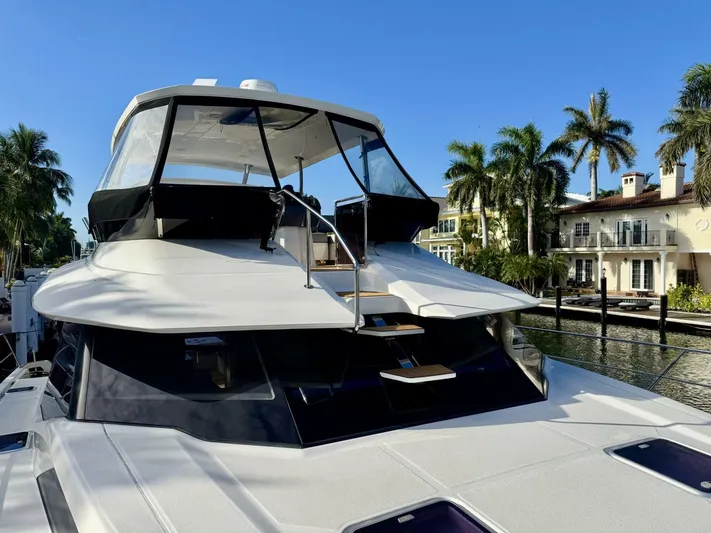 Roosterfish Yacht Photos Pics Aquila 44 yacht, 2022 model, docked near waterfront homes with palm trees.