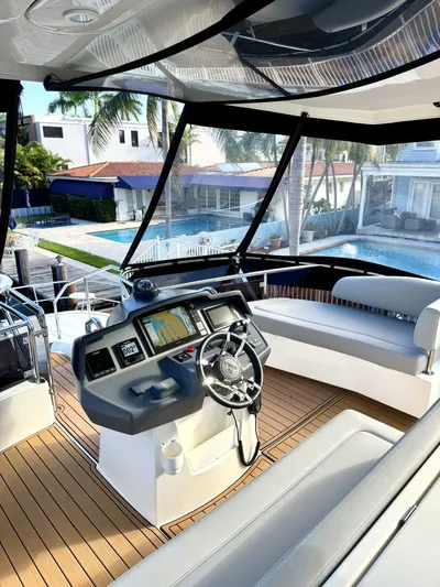 Roosterfish Yacht Photos Pics Luxury 2022 Aquila 44 yacht interior with modern helm and seating, overlooking waterfront homes.