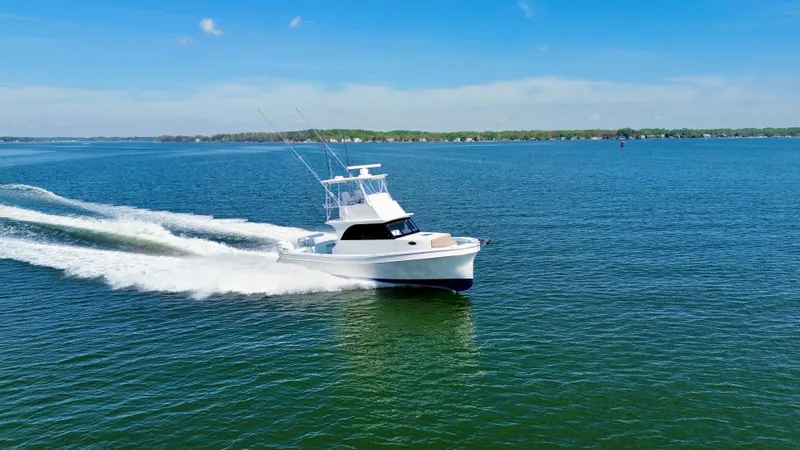 Reel Conversation Yacht Photos Pics 2023 Millennium Marine NuWave 37 cruising on a clear blue lake under a sunny sky.