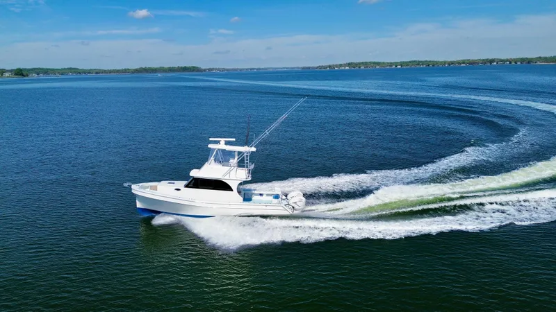 Reel Conversation Yacht Photos Pics 2023 Millennium Marine NuWave 37 cruising on a clear blue lake under a sunny sky.