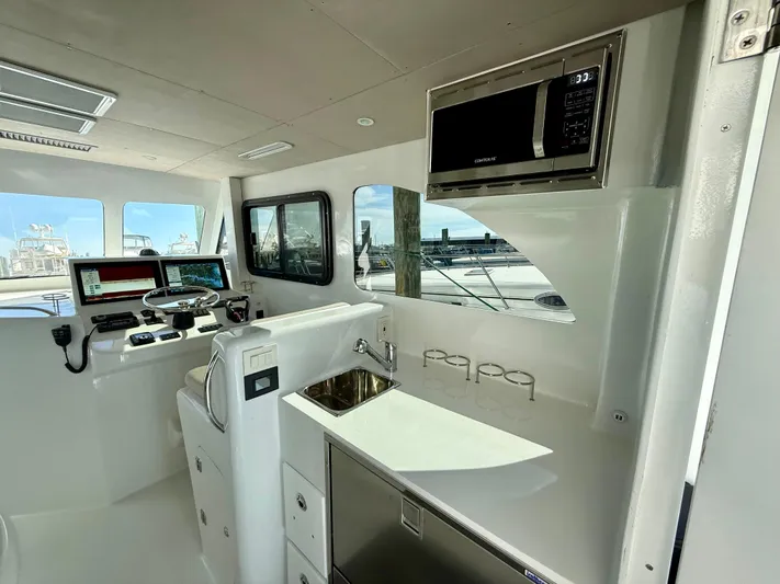 Reel Conversation Yacht Photos Pics Interior of 2023 Millennium Marine NuWave 37 boat with modern helm and kitchenette.