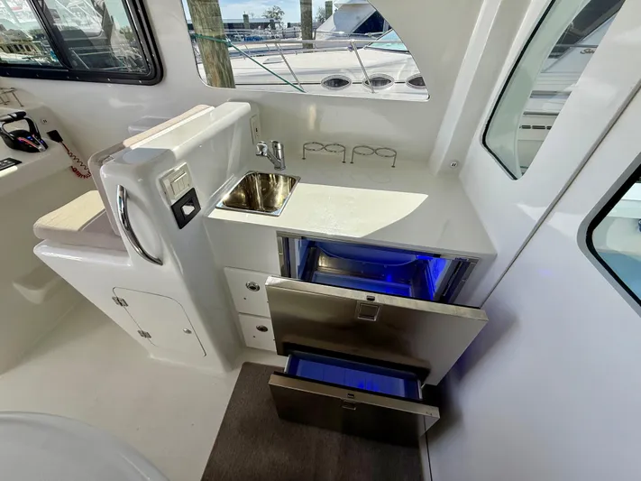 Reel Conversation Yacht Photos Pics Modern kitchenette in 2023 Millennium Marine NuWave 37 boat with sink and storage drawers.