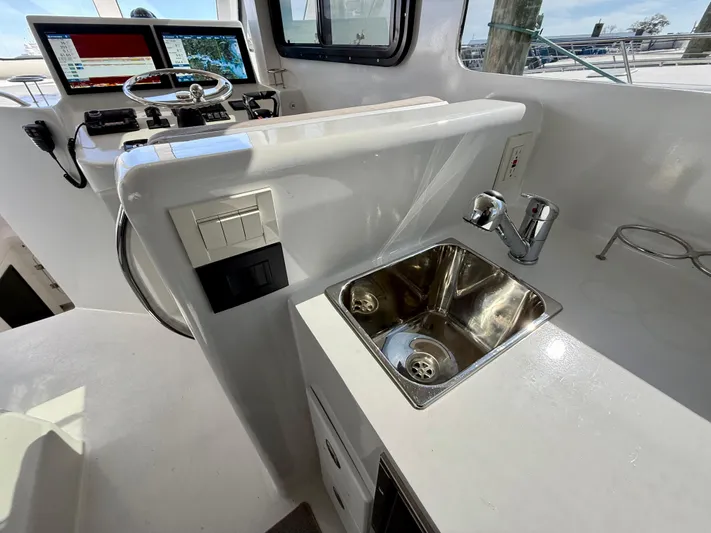 Reel Conversation Yacht Photos Pics 2023 Millennium Marine NuWave 37 boat interior with steering console and stainless steel sink.