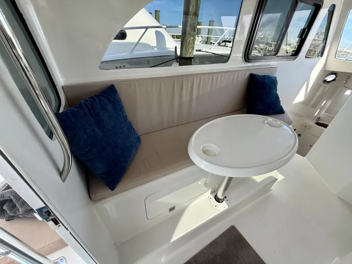 Reel Conversation Yacht Photos Pics 2023 Millennium Marine NuWave 37 interior with cushioned seating and round table.