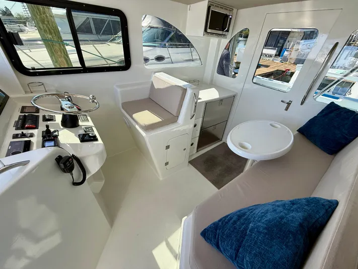 Reel Conversation Yacht Photos Pics Interior of 2023 Millennium Marine NuWave 37 boat with seating, control panel, and windows.