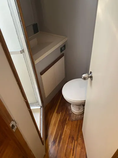  Yacht Photos Pics 1987 Bertram 50 Convertible yacht bathroom with wooden flooring and compact design.