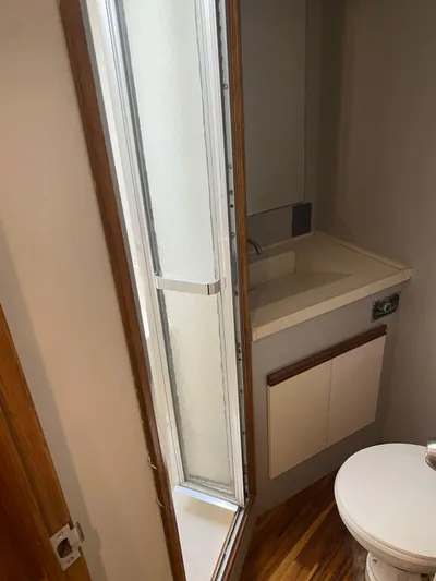  Yacht Photos Pics 1987 Bertram 50 Convertible yacht bathroom with sink, mirror, and toilet.