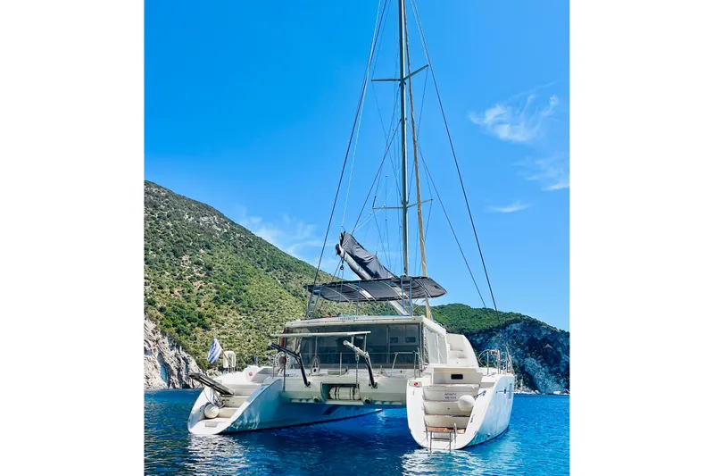  Yacht Photos Pics 2008 Lagoon 500 catamaran anchored in scenic blue waters with lush green hills.