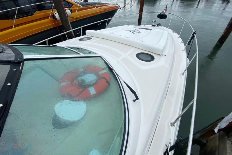  Yacht Photos Pics 2004 Sea Ray 340 Sundancer yacht with lifebuoy on deck, docked in rainy weather.