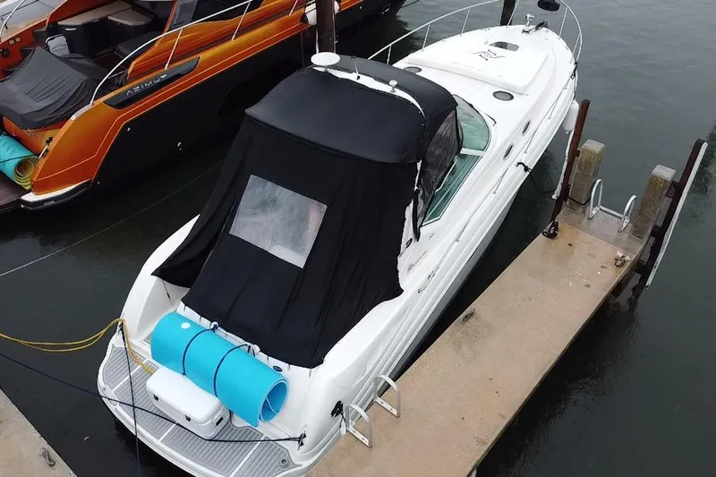 Yacht Photos Pics 2004 Sea Ray 340 Sundancer docked, featuring a black canopy and blue floatation devices.