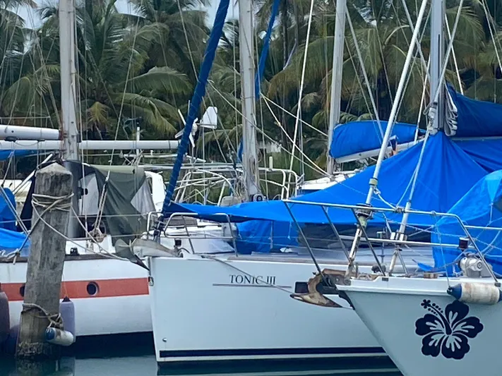 Sv Tonic III Yacht Photos Pics Beneteau Oceanis 41.1 sailboat docked, surrounded by palm trees, with blue tarps.
