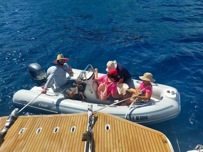 Oe Hani Yacht Photos Pics Small boat with people near a Leopard 58 yacht, 2018, on clear blue water.