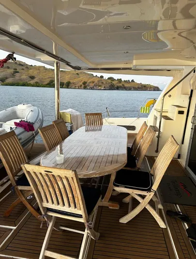 Oe Hani Yacht Photos Pics Outdoor dining area on a 2018 Leopard 58 yacht, overlooking serene waters and distant hills.