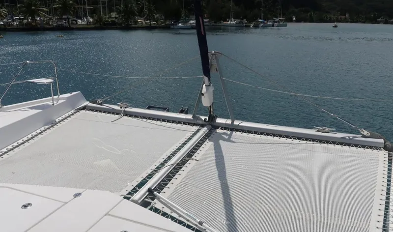 Oe Hani Yacht Photos Pics Front deck of 2018 Leopard 58 catamaran with netting, overlooking calm waters and distant shoreline.