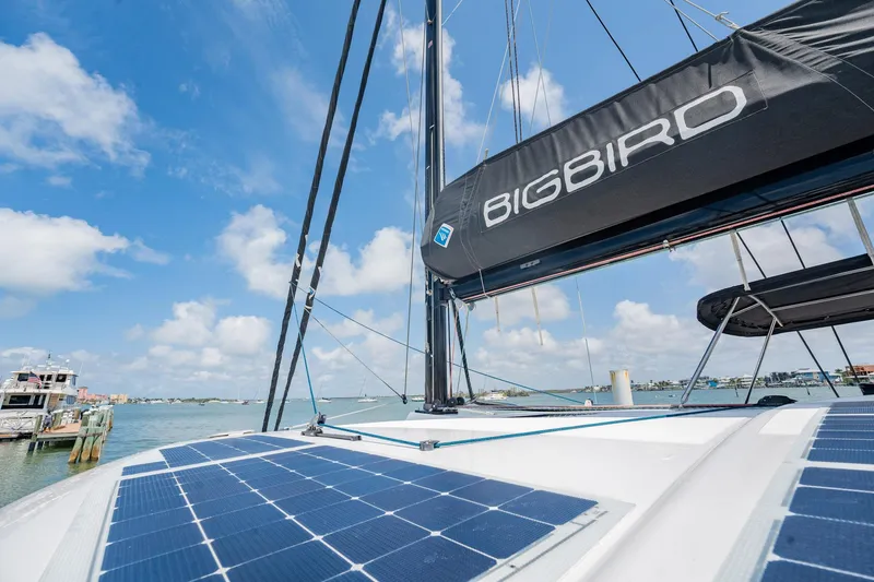 Big Bird Yacht Photos Pics Sailing trimaran NEEL 47 with solar panels, clear sky, and water view.