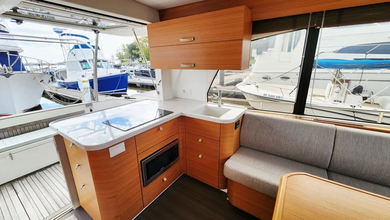 Sea-solar Sue & Lectric Lee Yacht Photos Pics Modern kitchen interior of 2022 Greenline 40 yacht with wood cabinetry and marina view.