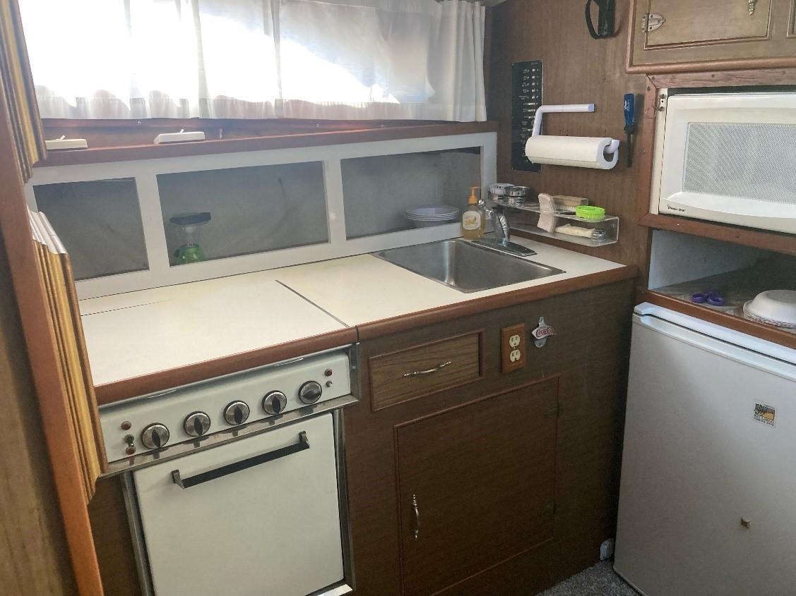 Compact kitchen in a 1969 Pacemaker 33 boat with stove, sink, and microwave.