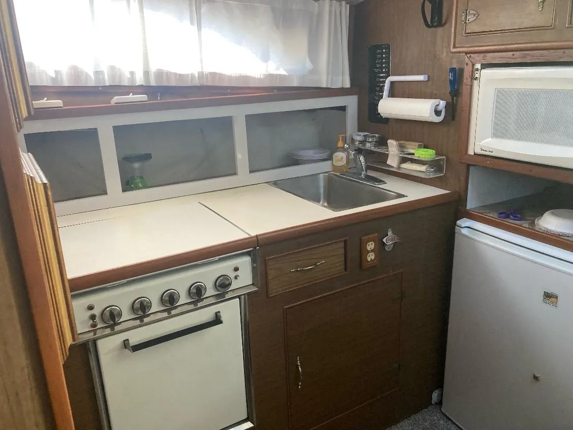 Compact kitchen in a 1969 Pacemaker 33 boat with stove, sink, and microwave.
