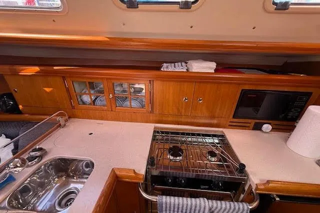 Yacht Photos Pics Interior view of a 2005 Hunter 38 yacht kitchen with stove, sink, and wooden cabinetry.