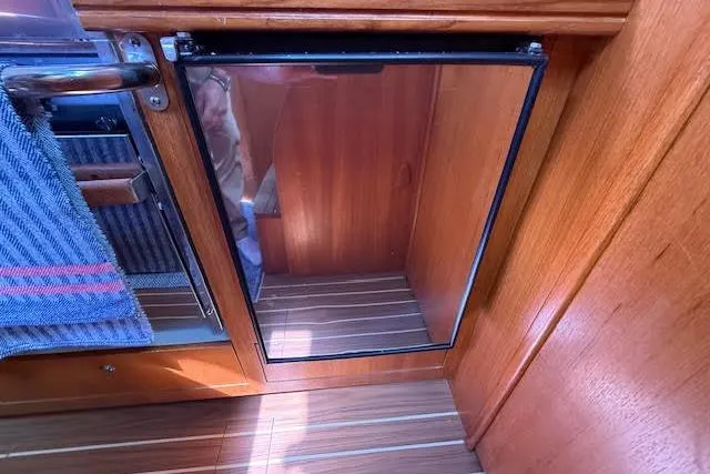  Yacht Photos Pics Wooden interior of a 2005 Hunter 38 sailboat, featuring a compact fridge.