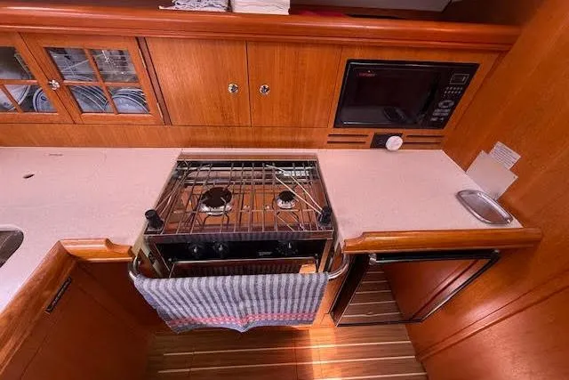  Yacht Photos Pics 2005 Hunter 38 yacht kitchen with stove, microwave, and wooden cabinetry.