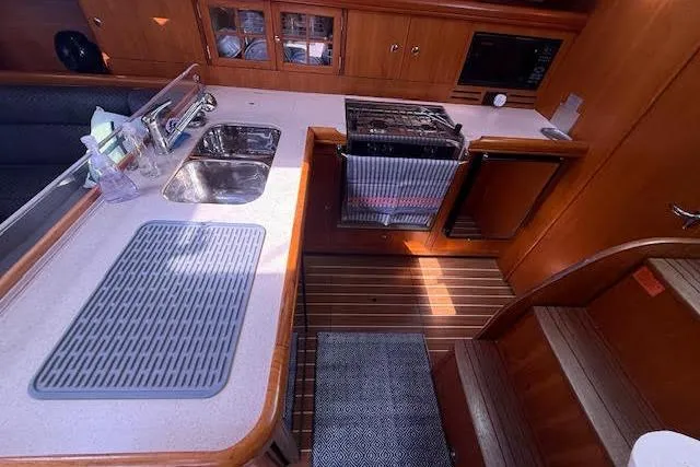  Yacht Photos Pics 2005 Hunter 38 yacht interior kitchen with sink, stove, and wooden cabinetry.