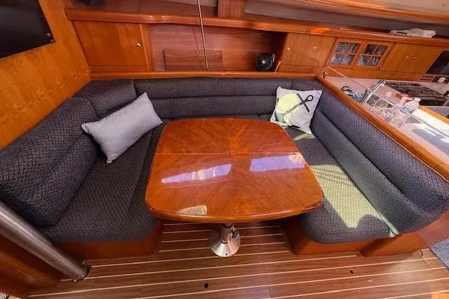  Yacht Photos Pics Cozy interior of 2005 Hunter 38 sailboat with wooden table and cushioned seating.