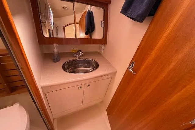  Yacht Photos Pics 2005 Hunter 38 yacht bathroom with sink, mirror, and wooden cabinetry.