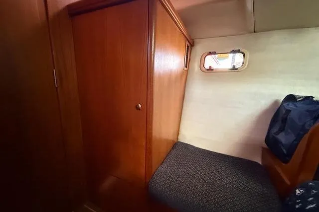 Yacht Photos Pics Cozy cabin interior of 2005 Hunter 38 sailboat with wooden paneling and small window.