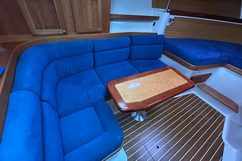 Solitude Yacht Photos Pics 2008 Back Cove 33 interior with blue seating, wooden table, and striped flooring.