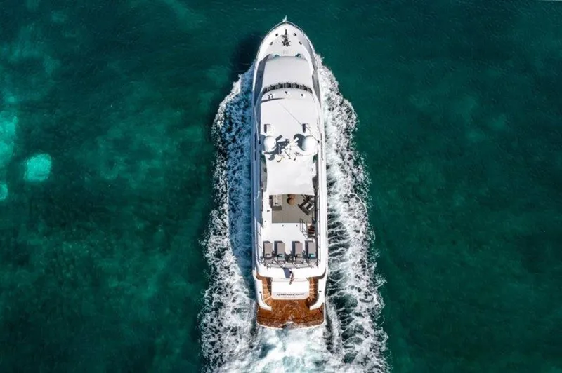 Claire Yacht Photos Pics Aerial view of 2003 Hatteras 100 yacht cruising in clear turquoise waters.