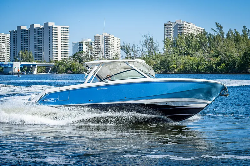  Yacht Photos Pics 2018 Boston Whaler 320 Vantage cruising on water with cityscape background.