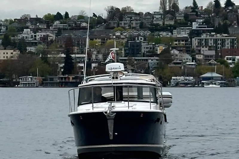 C Shell Yacht Photos Pics 2022 Ranger Tugs R-27 boat cruising on a lake with cityscape background.