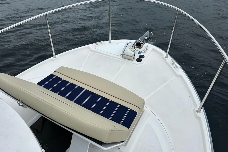 C Shell Yacht Photos Pics 2022 Ranger Tugs R-27 boat bow with cushioned seating and railing on water.