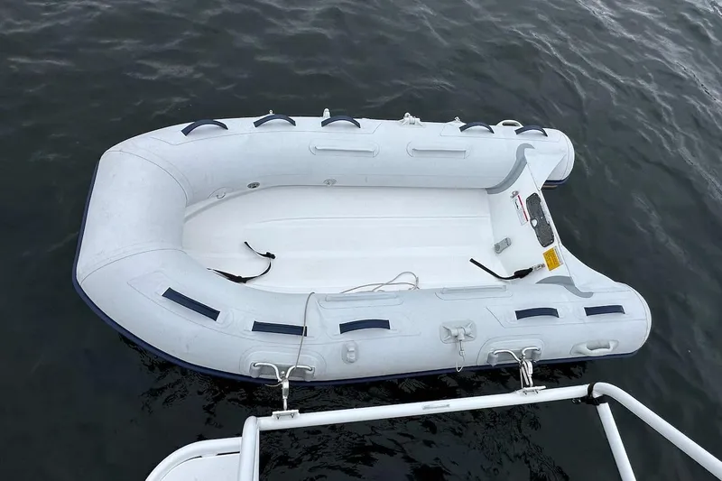 C Shell Yacht Photos Pics Inflatable dinghy floating on water near a 2022 Ranger Tugs R-27 boat.