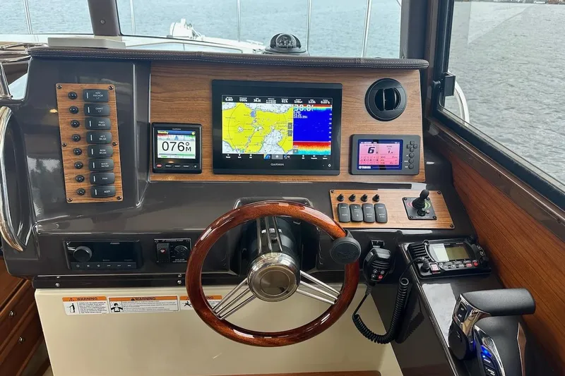 C Shell Yacht Photos Pics 2022 Ranger Tugs R-27 helm with navigation screens and controls, overlooking water.