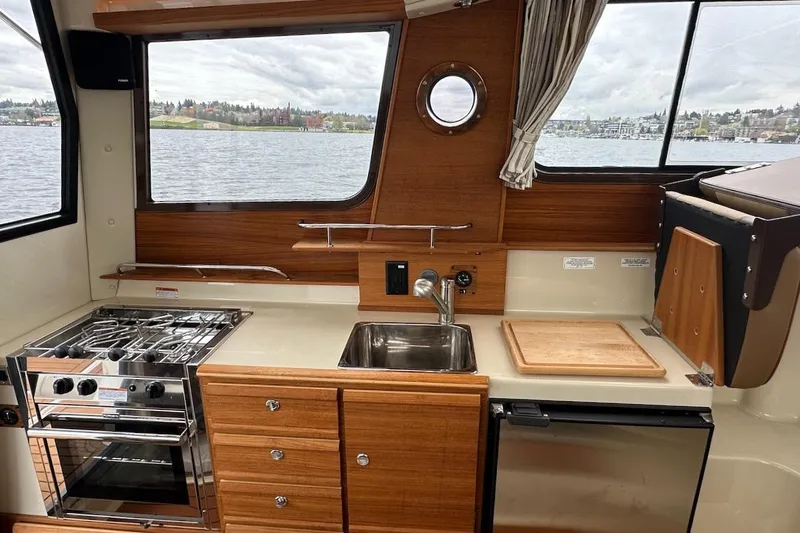 C Shell Yacht Photos Pics 2022 Ranger Tugs R-27 boat kitchen with stove, sink, and scenic window view.