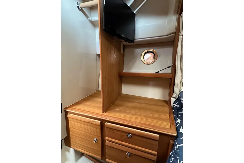 C Shell Yacht Photos Pics 2022 Ranger Tugs R-27 interior with wooden cabinetry, small TV, and porthole window.