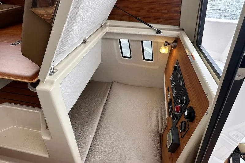 C Shell Yacht Photos Pics 2022 Ranger Tugs R-27 interior cabin with control panel and cozy sleeping area.