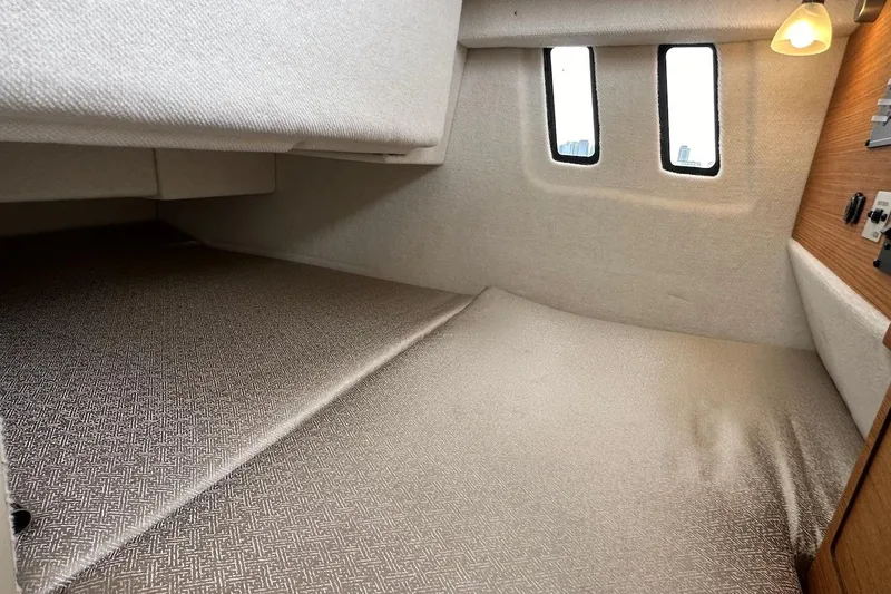 C Shell Yacht Photos Pics 2022 Ranger Tugs R-27 cabin interior with cozy bed and soft lighting.