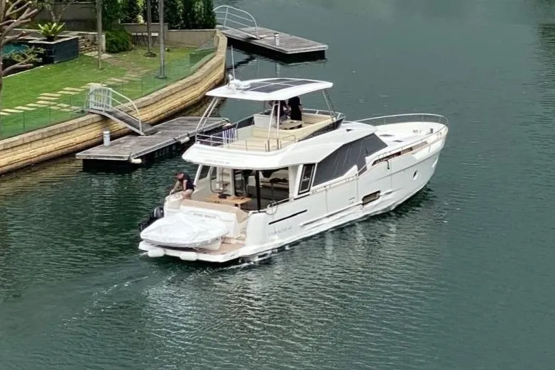  Yacht Photos Pics 2024 Greenline 48 Fly yacht cruising on a calm waterway near a dock.