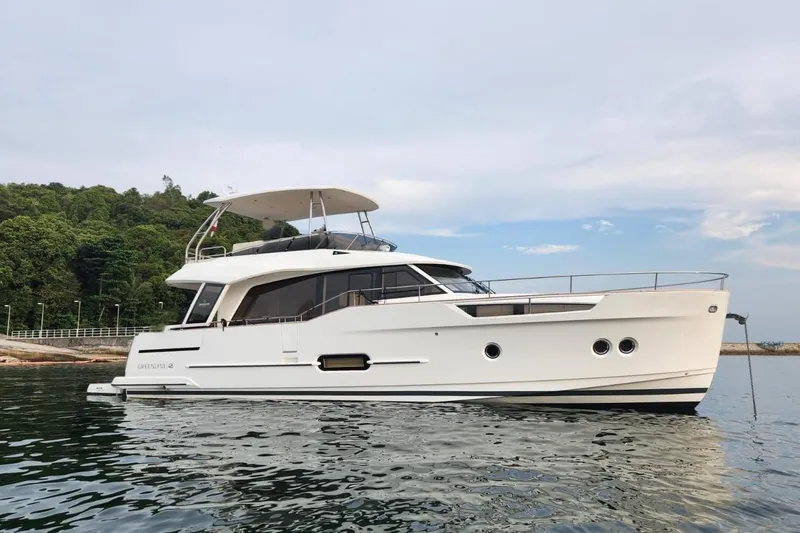  Yacht Photos Pics 2024 Greenline 48 Fly yacht on calm water, with lush greenery in the background.