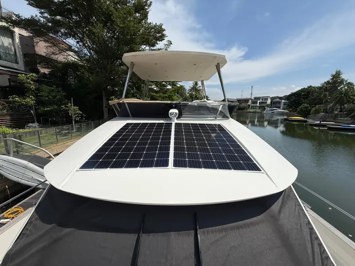 Yacht Photos Pics 2024 Greenline 48 Fly yacht with solar panels on deck, docked by a scenic waterfront.