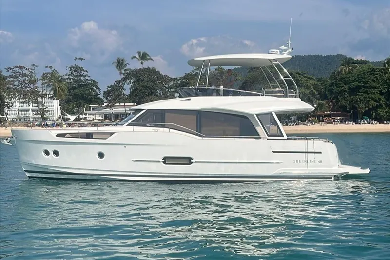  Yacht Photos Pics 2024 Greenline 48 Fly yacht on serene water near a tropical beach.
