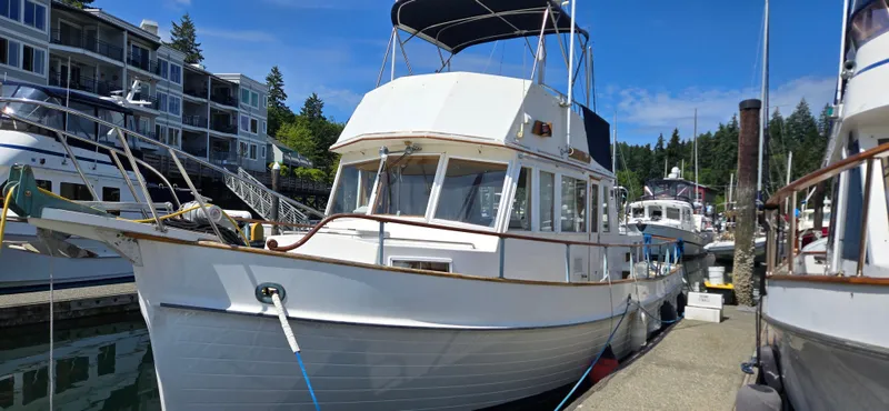 Grand Finale Yacht Photos Pics 1991 Grand Banks 36 Classic yacht docked at marina, surrounded by modern buildings and lush greenery.