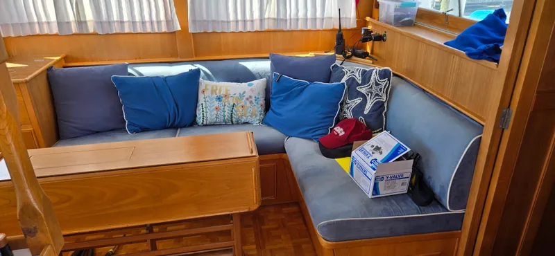 Grand Finale Yacht Photos Pics Interior of 1991 Grand Banks 36 Classic with blue cushions and wooden table.