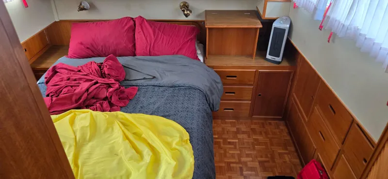 Grand Finale Yacht Photos Pics Cozy bedroom interior of 1991 Grand Banks 36 Classic with wooden cabinetry and colorful bedding.