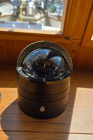 Grand Finale Yacht Photos Pics Compass on 1991 Grand Banks 36 Classic boat, wooden interior, sunlight reflection.