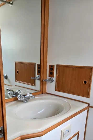 Grand Finale Yacht Photos Pics Bathroom sink area in a 1991 Grand Banks 36 Classic yacht, featuring wood accents and mirror.